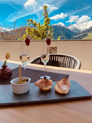 a table with two donuts and two glasses of wine at Hotel Alpenland in Moso