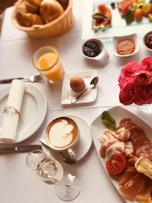 a table with plates of food and a cup of coffee at Hotel Alpenland in Moso