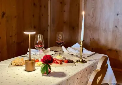 a table with a candle and two glasses of wine at Hotel Alpenland in Moso