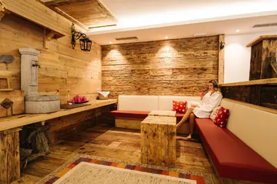 a woman sitting on a bench in a room with wooden walls at Hotel Alpenland in Moso