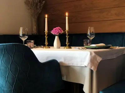a table with two candles and a vase of flowers on it at Hotel Alpenland in Moso