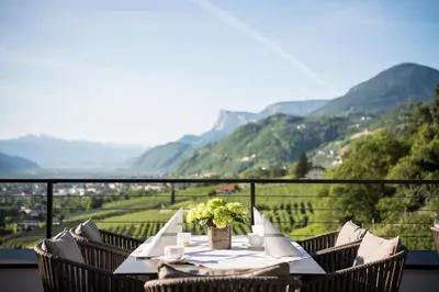 a table on a balcony with a view of a valley at Das Grafenstein Familienresidence in Cermes