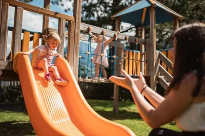 a woman taking a picture of a child on a slide at Das Grafenstein Familienresidence in Cermes