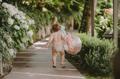 a little baby walking down a sidewalk holding an umbrella at Das Grafenstein Familienresidence in Cermes