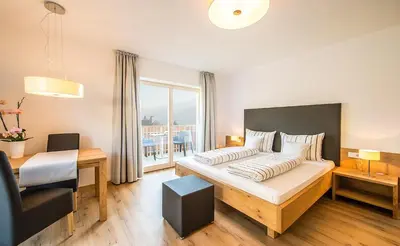 a bedroom with a bed and a table and a desk at Residence Wiesenhof in Vollan