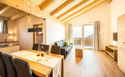 a living room with a dining room table and a kitchen at Residence Wiesenhof in Vollan