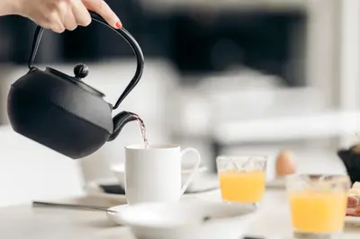 a person pouring coffee into a cup on a table at Villa Weingarten in Caldaro