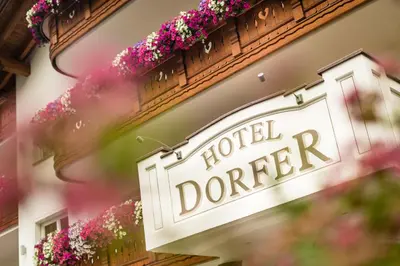a sign on the side of a building with flowers at Hotel Dorfer Alpine&Charming in Selva di Val Gardena