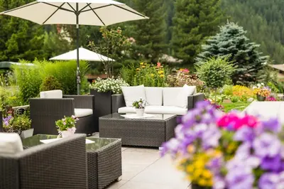 a patio with chairs and umbrellas and flowers at Hotel Dorfer Alpine&Charming in Selva di Val Gardena