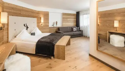 a bedroom with a large bed and a couch at Hotel Dorfer Alpine&Charming in Selva di Val Gardena