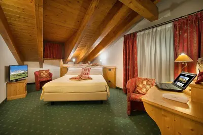 a hotel room with a bed and a desk with a laptop at Hotel Cristallo in Passo San Pellegrino