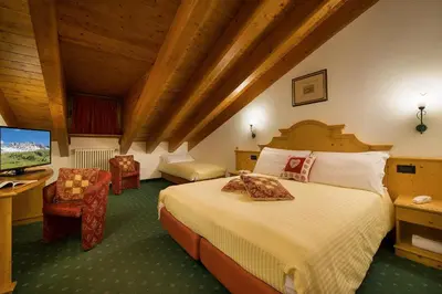 a bedroom with a bed and a desk with a television at Hotel Cristallo in Passo San Pellegrino