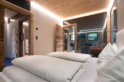 a bedroom with two white beds and a living room at Neuprantl Apartments in Lana