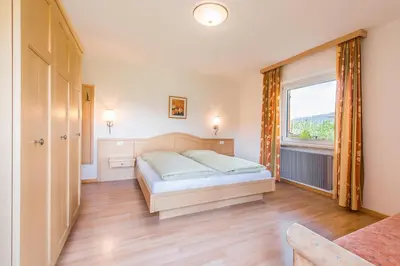 a bedroom with a bed and a large window at Residence Hoferhof in Lana
