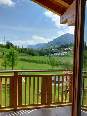 a balcony with a view of a green field and mountains at Residence Hoferhof in Lana