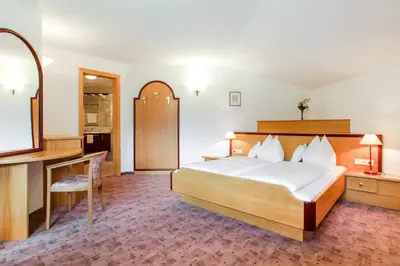 a bedroom with a bed and a desk and a mirror at Das Bergland - Vital & Activity in San Leonardo in Passiria