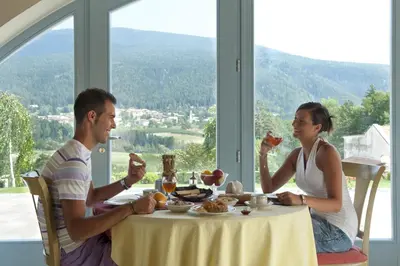 a man and woman sitting at a table with wine glasses at La Quiete Resort in Romeno