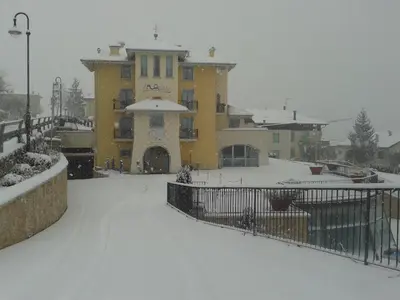 a large yellow building with snow on the ground at La Quiete Resort in Romeno