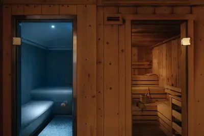 a sauna with wooden walls and a glass door at Hotel La Montanara Predazzo in Predazzo