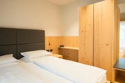 a bedroom with a large white bed and wooden walls at Hotel La Montanara Predazzo in Predazzo