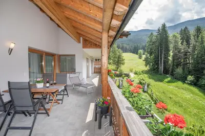 an outdoor patio with chairs and a table and flowers at Apartmenthaus Fuchsmaurer in Bressanone