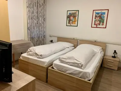 two twin beds in a room with a tv at B&B Hotel Dolomiti in Bolzano