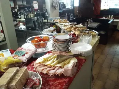 a buffet with plates and other food on a table at B&B Hotel Dolomiti in Bolzano