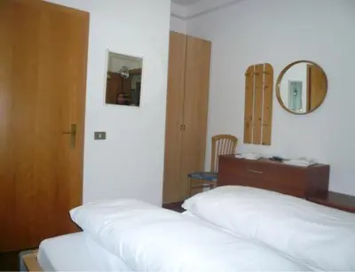 a bedroom with a bed and a dresser and a mirror at B&B Hotel Dolomiti in Bolzano