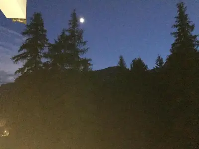 a moon in the sky over some trees at night at I mughi - Cortina in Cortina dʼAmpezzo