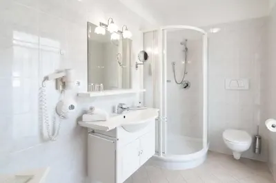 a white bathroom with a sink and a shower at Hotel Villa Groff in Ora/Auer