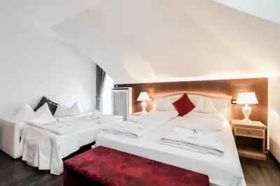 two beds in a hotel room with a red bench at Hotel Villa Groff in Ora/Auer