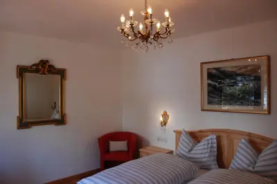 a bedroom with a bed and a mirror and a chair at Villa Moroder in Ortisei