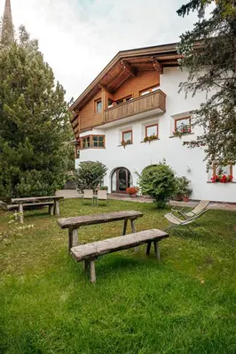 a building with benches in the grass in front of it at Villa Moroder in Ortisei