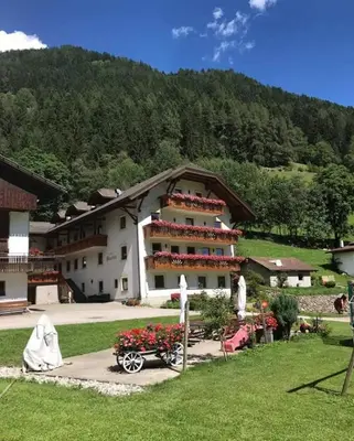 a large building with a wagon in front of it at Hotel Pension Moarhof in Vallarga