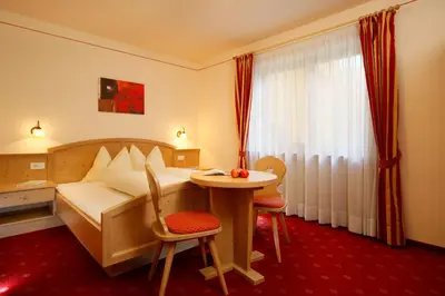 a hotel room with a bed and a table and chairs at Residence Ulrike in Nova Levante
