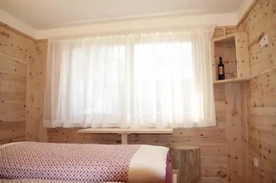 a bedroom with a bed and a window with a curtain at Lehrnerhof Lüsen in Luson