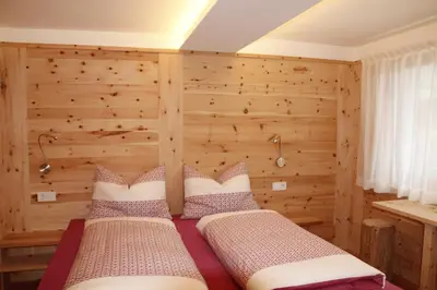two beds in a room with a wooden wall at Lehrnerhof Lüsen in Luson