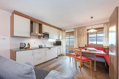 a kitchen with a table and red chairs in a room at Harrerhof in Perca