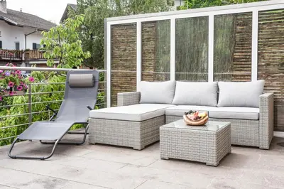a wicker couch and a chair on a patio at Appartements Sonneck in Funes
