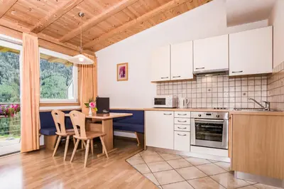 a kitchen with white cabinets and a table and chairs at Appartements Sonneck in Funes