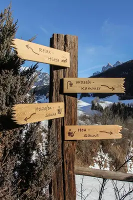 a wooden sign on a wooden pole with signs on it at Appartements Sonneck in Funes