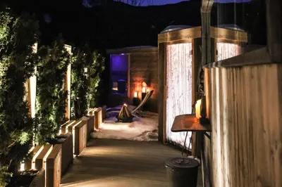 a wooden walkway leading to a cabin in the snow at night at Appartements Sonneck in Funes