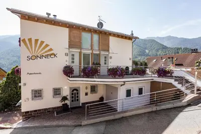 a building with a balcony with flowers on it at Appartements Sonneck in Funes