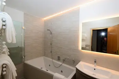 a bathroom with a tub and a sink and a mirror at Residence Albierch in Ortisei