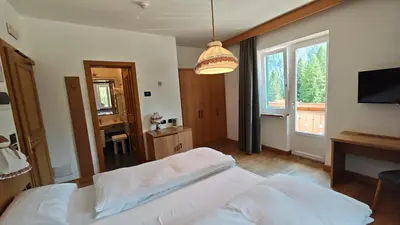 a bedroom with a bed and a large window at Hotel Roy in Malga Ciapela