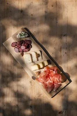 a table with cheese and meats on a cutting board at Vigilius Mountain Resort in Lana