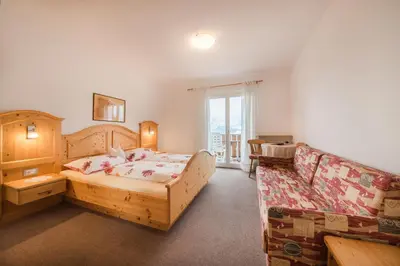 a bedroom with a bed and a couch at Garni Georgenhöhe in Schenna
