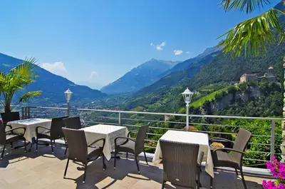 a patio with tables and chairs and a view of mountains at Villa Maria in Tirolo