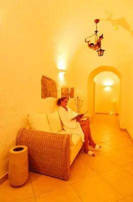 a woman sitting on a couch reading a book at Villa Maria in Tirolo