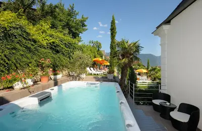 a swimming pool in a backyard with chairs and umbrellas at Villa Maria in Tirolo